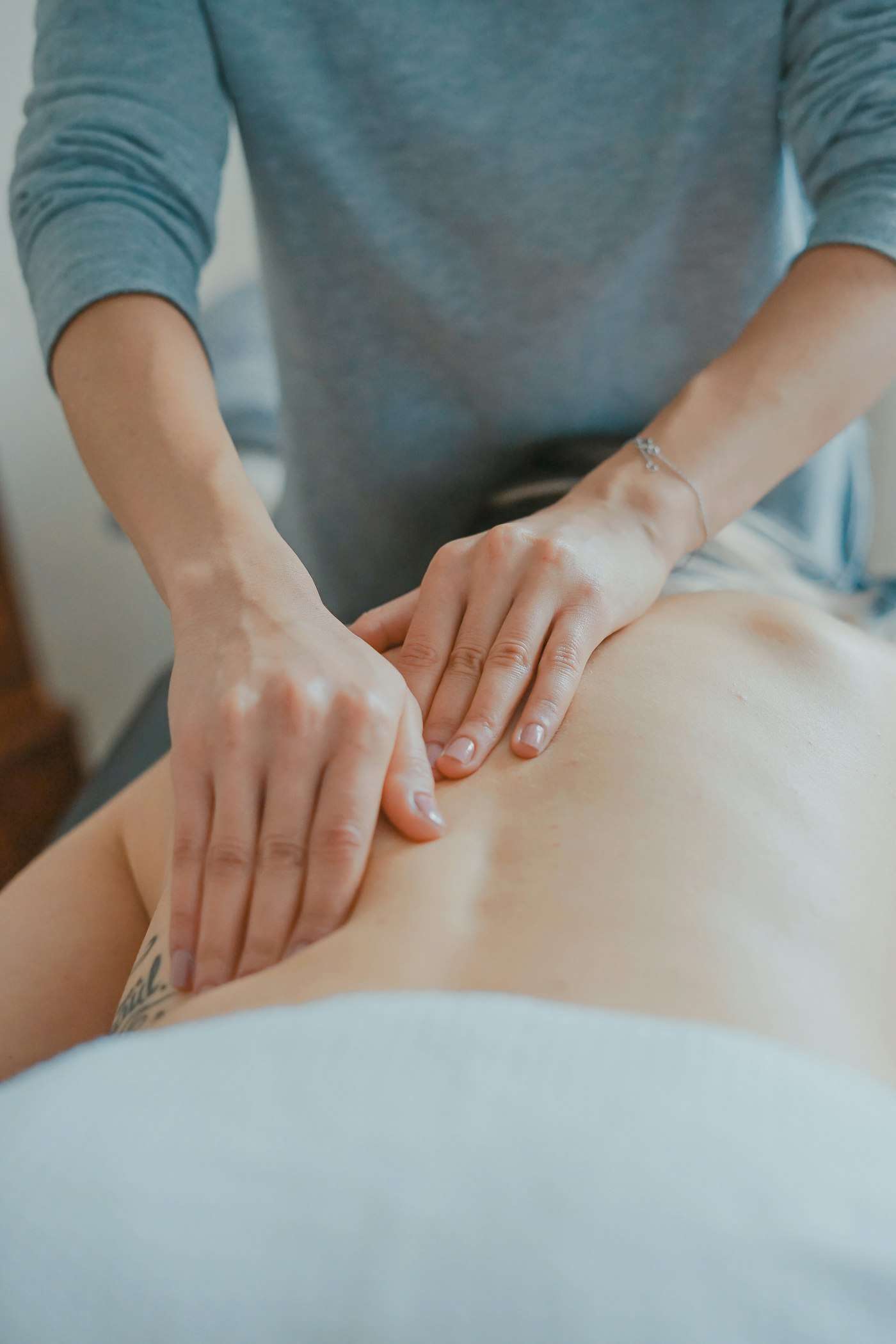 Masseuse in white working on a back with both hands
