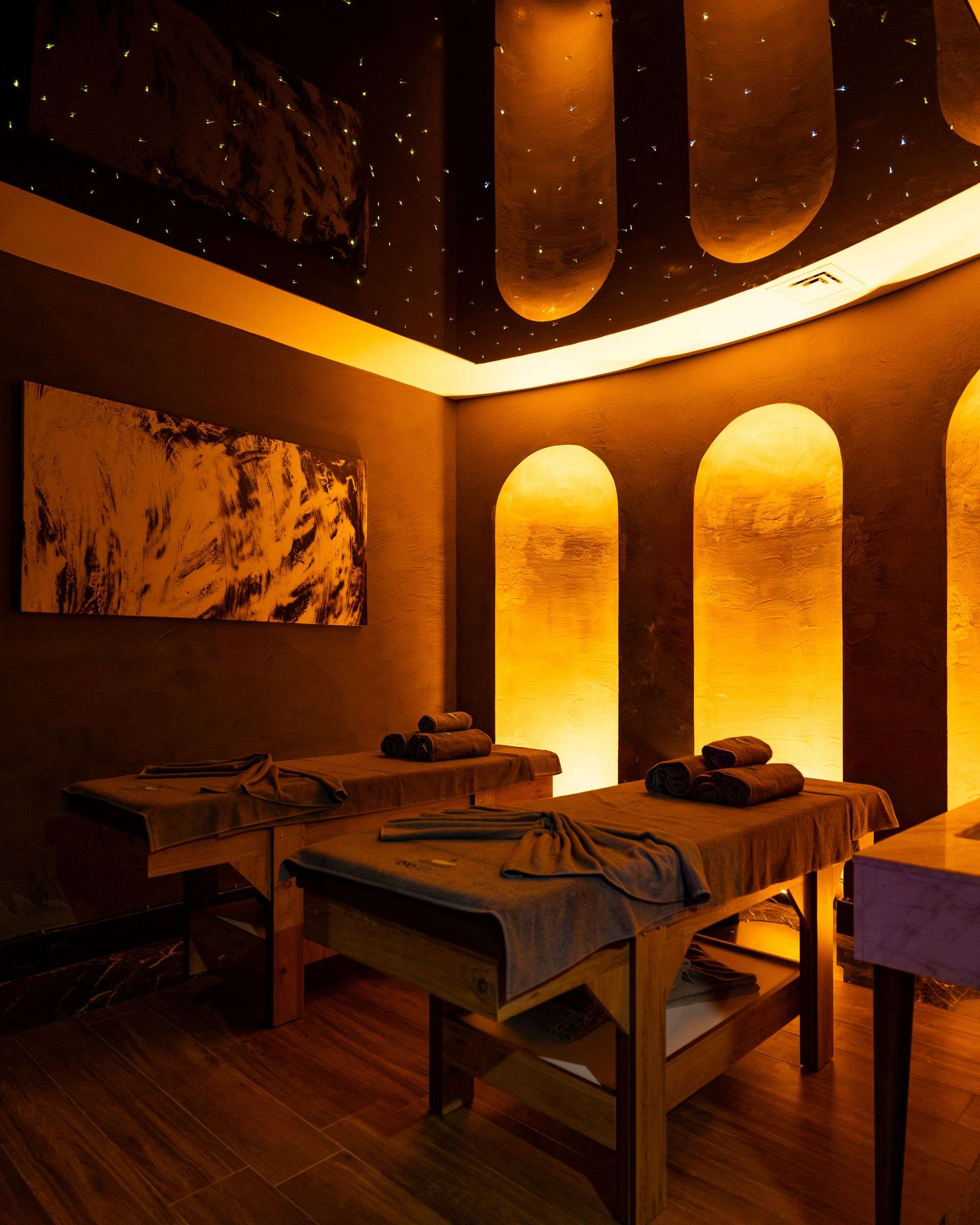 Treatment room with two massage tables side by side, warm light and folded towels