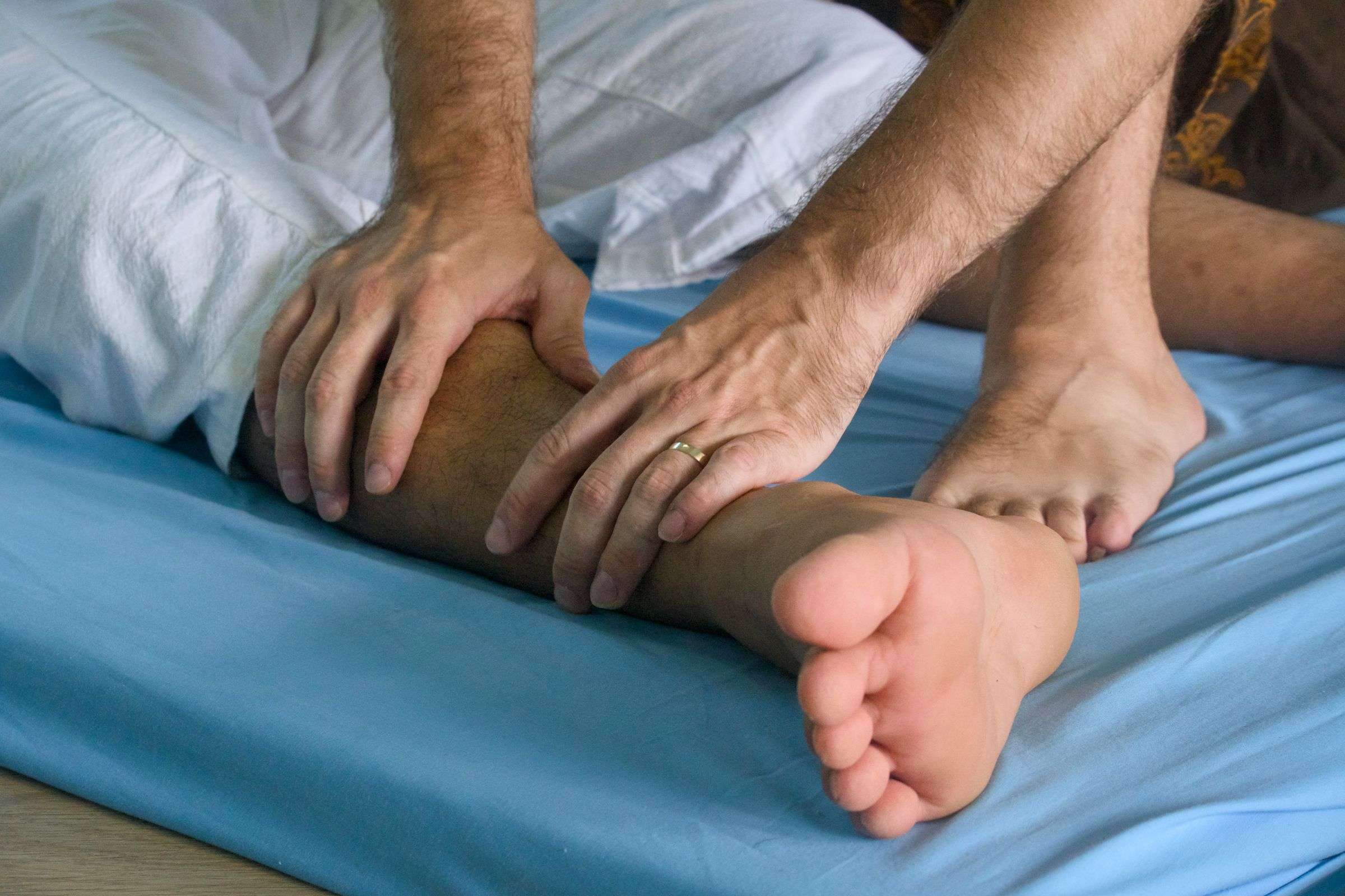 Two hands pressing on a lower leg, during a Thai massage