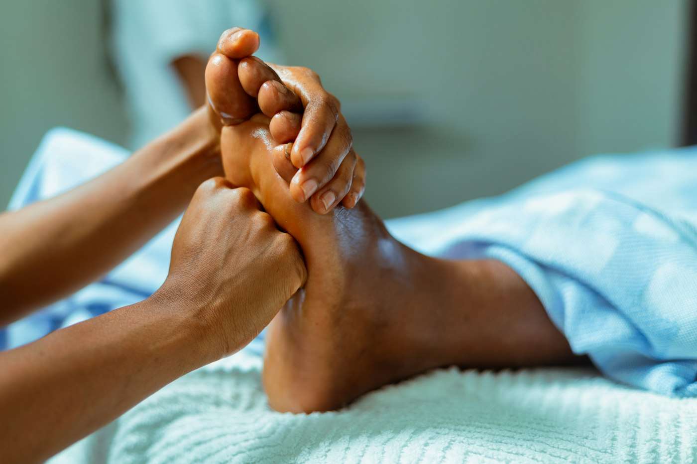 Hands massaging a foot on a blue towel